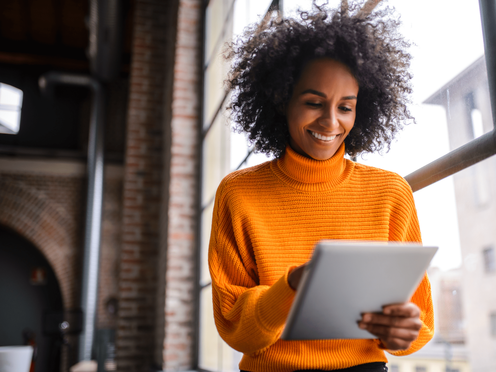 lady in orange jumper looking at tablet